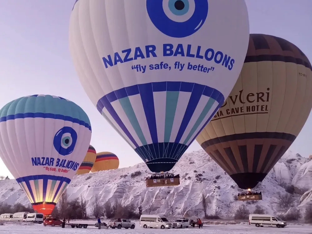 Hot air balloons over Cappadocia on a snowy day Nazar Balloons