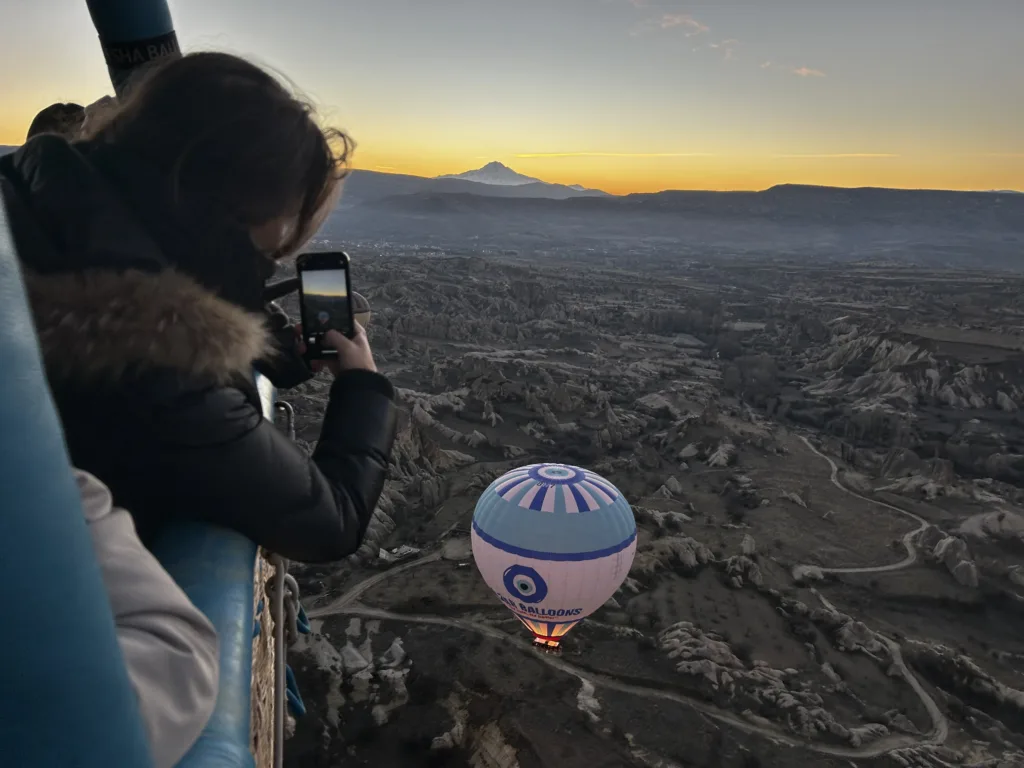 Woman on Nazar Balloons Flight taking photo of sunrise in Cappadocia on Sunrise Flight over Göreme