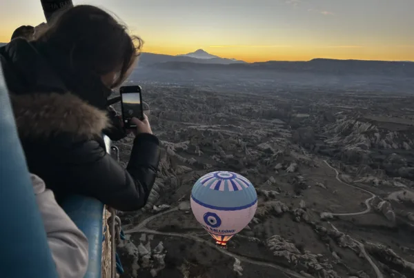 Woman on Nazar Balloons Flight taking photo of sunrise in Cappadocia on Sunrise Flight over Göreme